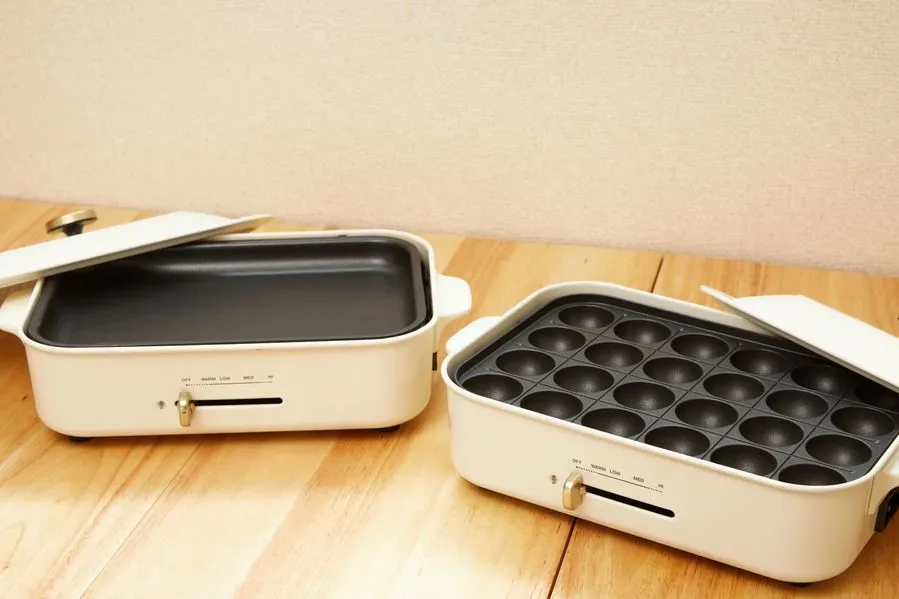 天六店の木のテーブルに並んだ白いホットプレート2台。左は平らなプレート、右はたこ焼き用の丸いくぼみが並ぶプレート