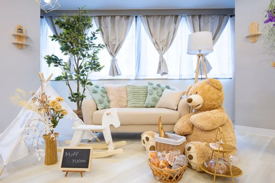 Moff room三宮店の遊びスペース。ベージュのソファに大きなくまのぬいぐるみが座り、白い木馬とキッズテント、ドライフラワーが並んでいる