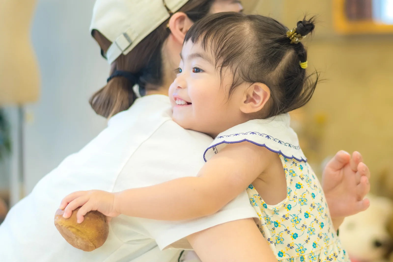 大人に抱かれた子どもの横顔と手元を近くから写した提供写真